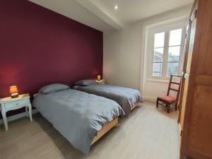 een slaapkamer met 2 bedden en een rode muur bij Gîte Saint-Haon-le-Châtel, 4 pièces, 11 personnes - FR-1-496-252 in Saint-Haon-le-Châtel