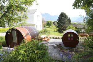 two circular structures in a garden with a house at Schlaf-Fass Jenins in Jenins