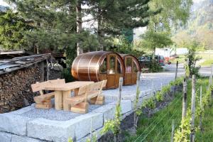 een houten tafel en bank naast een vat bij Schlaf-Fass Maienfeld in Maienfeld