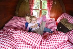 Zwei Kinder sitzen auf einem Bett in einem Zimmer in der Unterkunft Schlaf-Fass Maienfeld in Maienfeld