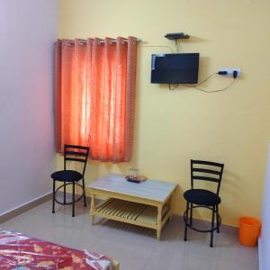 Habitación con mesa, 2 sillas y TV. en Bimala Hotel, en Ranchi