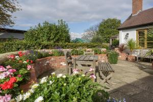 a garden with a bench and a bunch of flowers at Bay Tree Cottage in Droitwich