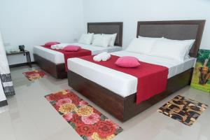 2 Betten in einem Zimmer mit roter Bettwäsche in der Unterkunft Sadee's Place in Dambulla