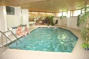Três raparigas estão sentadas numa piscina. em Hotel Haus Deutsch Krone em Bad Essen