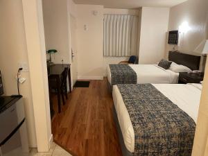 Cette chambre comprend deux lits et un bureau. dans l'établissement Sunbeam Motel, à San Luis Obispo
