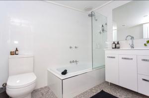 Un baño blanco con inodoro y bañera. en Cowra Cottage, en Cowra 15 fotos más