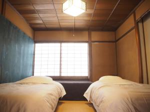 dwa łóżka w pokoju z oknem w obiekcie Guest House SUETUGU w mieście Matsue