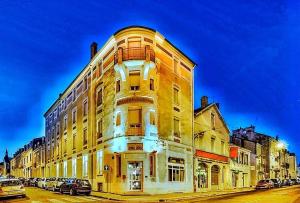 a tall yellow building on a city street at The Originals City, Hôtel Régina, Périgueux in Périgueux
