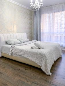 een slaapkamer met een wit bed en een kroonluchter bij 2к квартира на Академгородке in Kiev