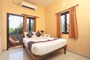 a bedroom with a bed and two windows at Hotel Castle Manor - Auroville Beach in Pondicherry