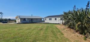 a house with a large yard in front of it at Rarakau Lodge in Tuatapere