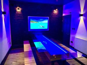 a room with a tv and a table in a room with purple lights at Saltrock luxury apartment in Blackpool