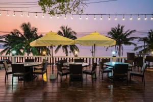 a patio with tables and chairs and umbrellas at RimLay Beachfront Pool Villa in Sattahip