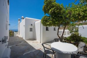 a table and chairs in front of a white building at Zisis Pension in Agios Stefanos