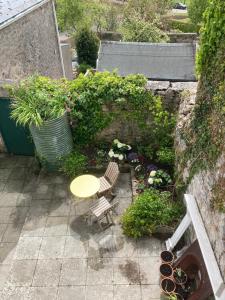 un patio con mesa, sillas y plantas en Long Meadow Bakery en Pembrokeshire