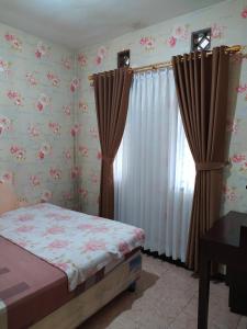 a bedroom with a bed and a window with curtains at Villa Beverly in Lembang