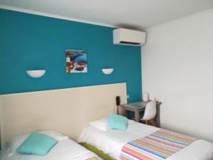 a bedroom with a blue wall and a bed and a desk at Contact Hôtel du Relais Thouars in Thouars +19 photos