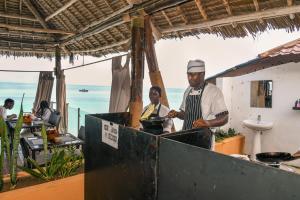 a couple of men cooking food on a grill at Amaan Beach Bungalows in Nungwi +85 photos