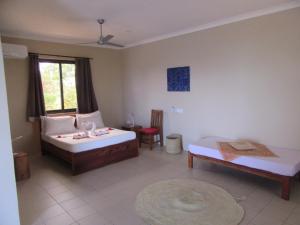 a bedroom with two beds and a table and a window at Coral House near Villa Bluu in Jambiani