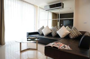 a living room with a black couch and a table at The Baycliff Residences in Patong Beach