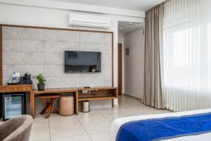 a hotel room with a desk and a television on a wall at Oshin Hotel in Wayanad