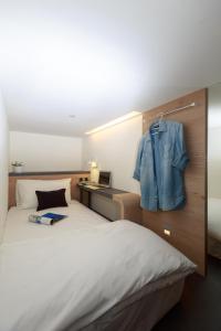 Taiwan Youth Hostel & Capsule Hotel في تايبيه: غرفة نوم مع سرير مع سترة زرقاء معلقة على الحائط