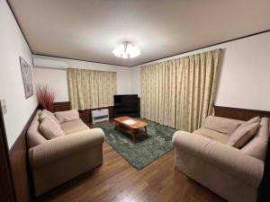 a living room with two couches and a table at Hakuba Mountain Chalet in Hakuba