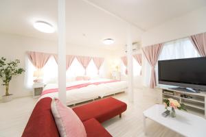 a white bedroom with a large bed and a red couch at Awaji Horiday Inn Kariya in Awaji