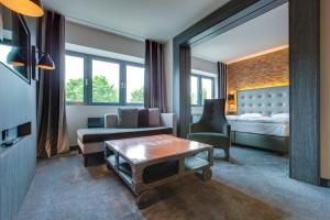 a living room with a bed and a couch and a table at Park Inn by Radisson Lübeck in Lübeck