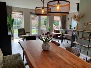 a living room with a table with a vase of flowers on it at Bosboerderij de Veluwe, luxe huisje in het bos in Lunteren