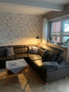 a living room with a brown leather couch and a table at Ferienhaus Staben in Eggstedt