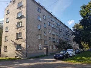 un grand bâtiment en briques avec des voitures garées devant lui dans l'établissement Teatra32 Sunshine Home, à Daugavpils