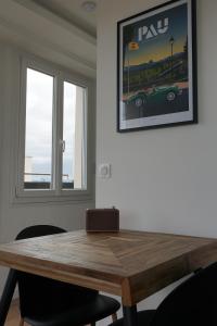 uma mesa de madeira num quarto com duas janelas em Ultra centre - Certainement la plus belle vue de Pau em Pau