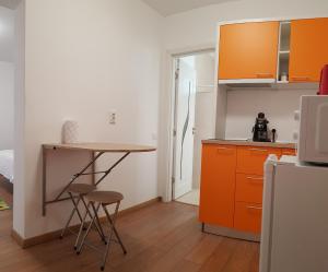 a kitchen with orange cabinets and a table and stools at Apartament 3 Budiu in Târgu-Mureş