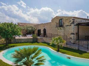 une villa avec une piscine en face d'un bâtiment dans l'établissement Masseria Fortificata Lo Zafferaneto, à Buccheri