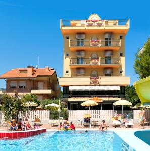 un hôtel avec une piscine en face d'un bâtiment dans l'établissement Hotel Caravel B&B, à Misano Adriatico