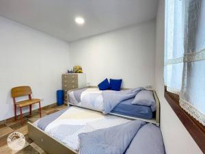 1 dormitorio con 2 camas, silla y ventana en Casa Zunbeltz de 3 habitaciones en plena montaña, en Lezáun