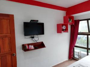 1 dormitorio con TV de pantalla plana en la pared en Evonne Budget Hotel, en Tanah Rata