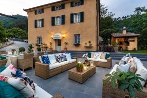 a patio with couches and tables in front of a building at Casolare dei Colli, Panoramic Private Pool, Lavish Interiors and a Gourmet Kitchen in Camaiore