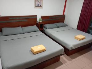 two beds in a room with two trunks at Evonne Budget Hotel in Tanah Rata