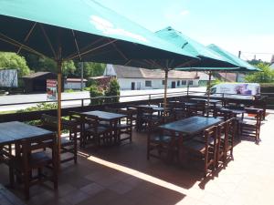 un grupo de mesas y sillas bajo una sombrilla verde en NEZNAŠOVY*** Restaurant-Penzion, en Vrhaveč