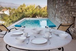 a table with plates and utensils next to a pool at Istron Luxury Villas in Istron