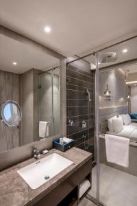 un bagno con lavandino e doccia e un letto di Radisson Blu Towers Kaushambi Delhi NCR a Ghaziabad