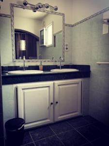 un bagno con due lavandini e un grande specchio di Les 2 roses De Verdillon a La Crau