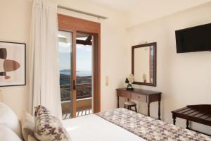 a bedroom with a bed and a desk and a mirror at Triopetra Luxury Villas Panagia in Triopetra