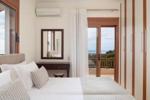 トリオペトラにあるTriopetra Luxury Villas Panagiaのベッドルーム(白いベッド1台、バルコニー付)