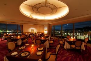 a restaurant with tables and chairs and a large window at Kure Hankyu Hotel in Kure