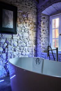 a bath tub in a room with a stone wall at Bolgheri Wine Suite in Bolgheri