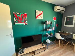 un salon avec un mur vert, une télévision et une table dans l'établissement Mickitos City Center Apartment, à Skopje