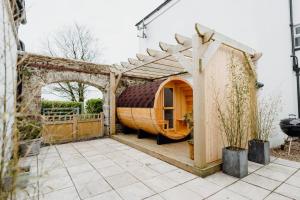 ein Holzhobbit-Haus mit einer Pergola in der Unterkunft The Bakehouse - Cosy conversion with Outdoor Sauna in Tenby